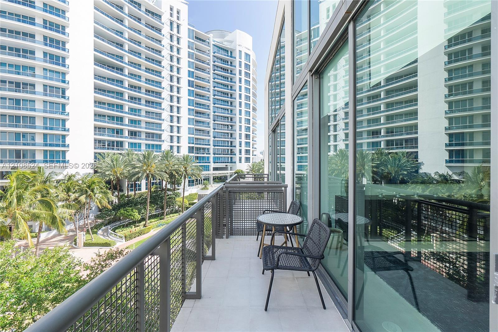 Covered balcony with large-format tile flooring, a structured metal mesh railing, and floor-to-ceiling glass panel walls