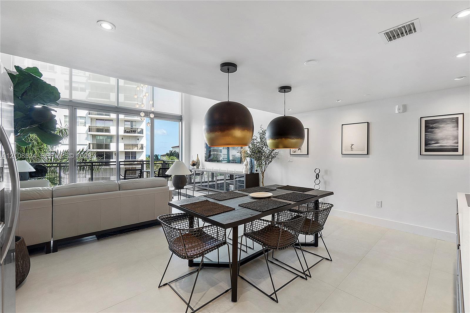 Open-concept interior featuring floor-to-ceiling glass windows, recessed ceiling lighting, light-toned tile flooring, and dual oversized dome pendant fixtures