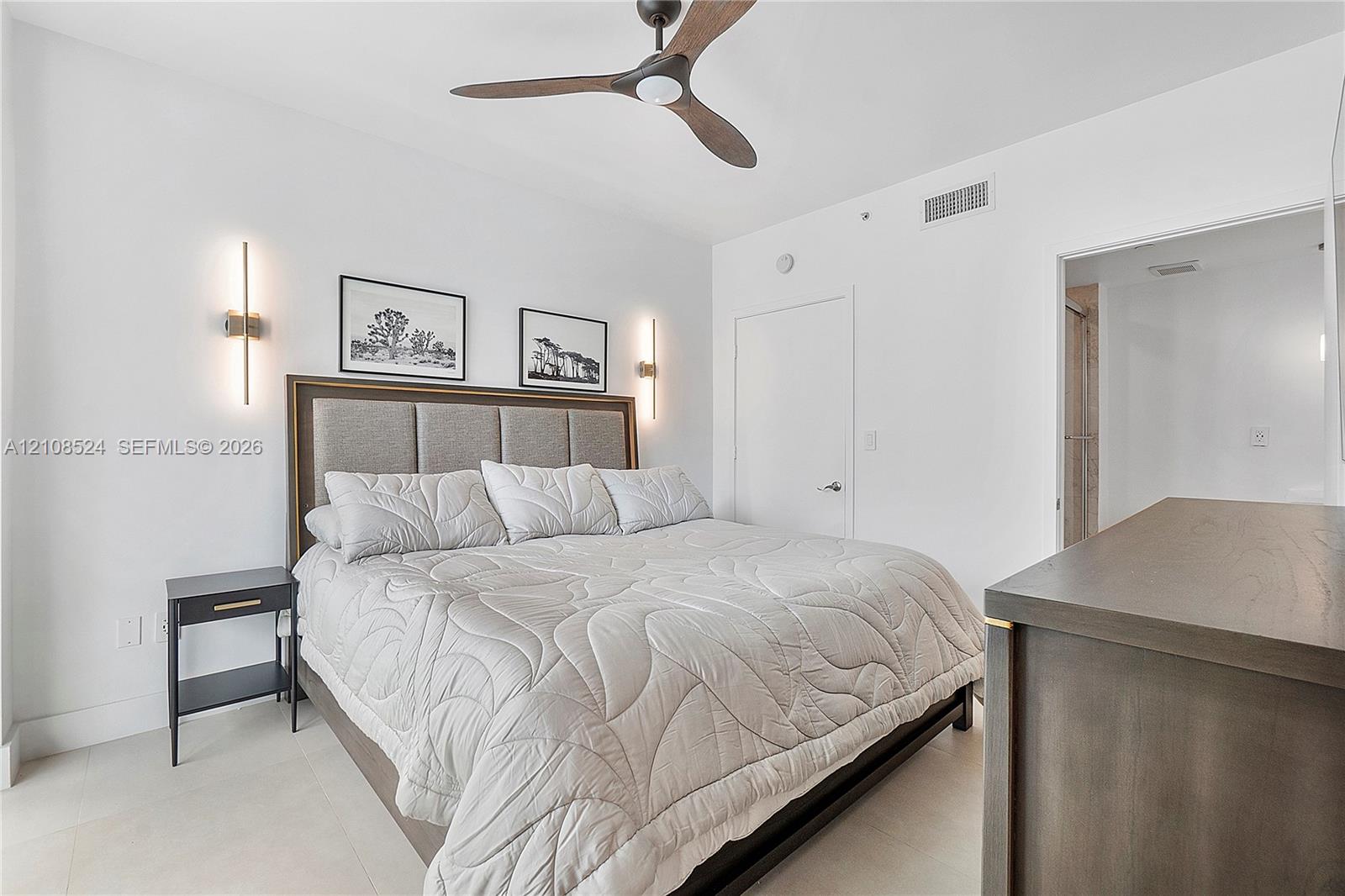 Room featuring a matte-finish three-blade ceiling fan, vertical wall-mounted lighting fixtures, and neutral flooring Room featuring a matte-finish three-blade ceiling fan, vertical wall-mounted lighting fixtures, and neutral flooring