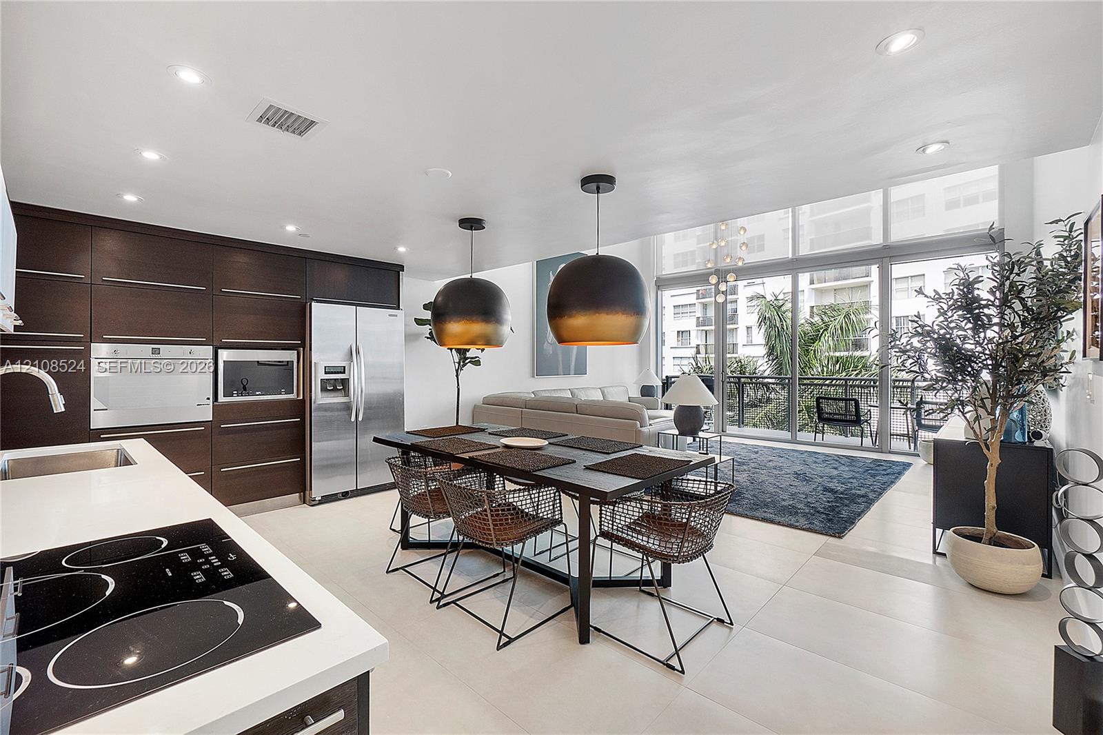 Kitchen featuring dark cabinetry, stainless steel appliances, white countertops, large-format tile flooring, and floor-to-ceiling windows
