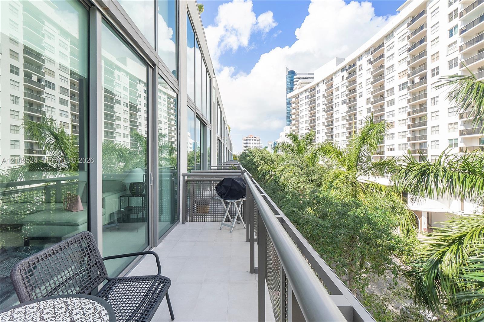 Covered terrace with tile flooring, floor-to-ceiling glass panel walls, and metal railings