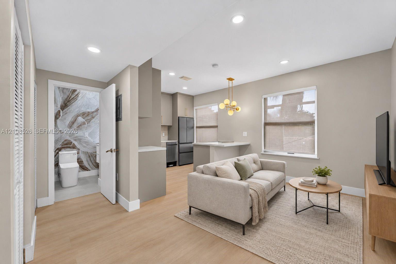 Open-concept interior featuring light wood-finish flooring, recessed lighting, and a modern kitchen with stainless steel appliances