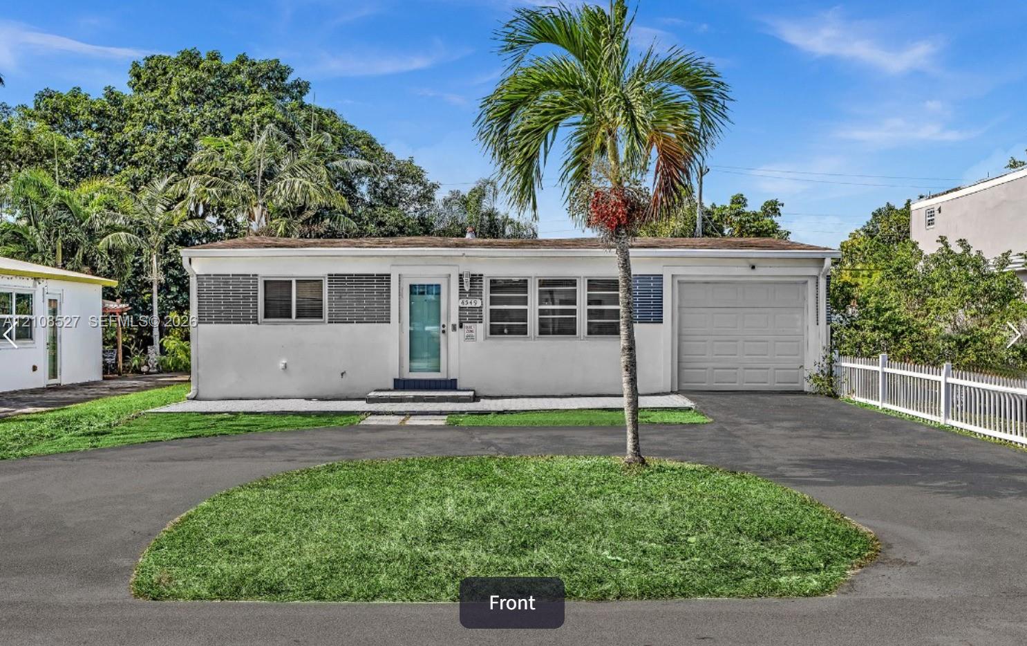 Exterior featuring a smooth-stucco finish, decorative metal shutters, an attached single-car garage, and a paved circular driveway