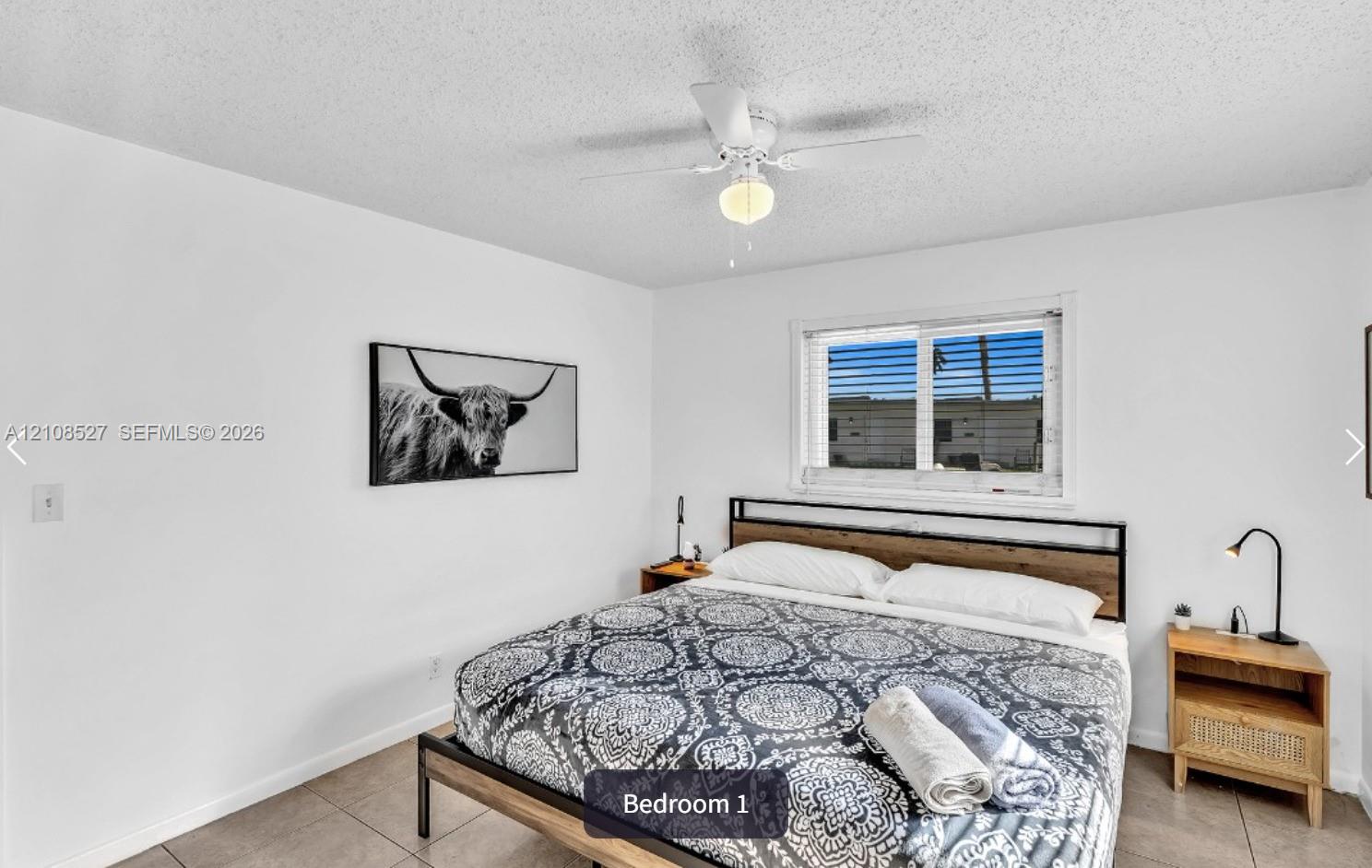 Neutral-toned interior featuring large-format tile flooring, a white ceiling-mounted light fixture with an integrated fan, and a single-hung window with white framing