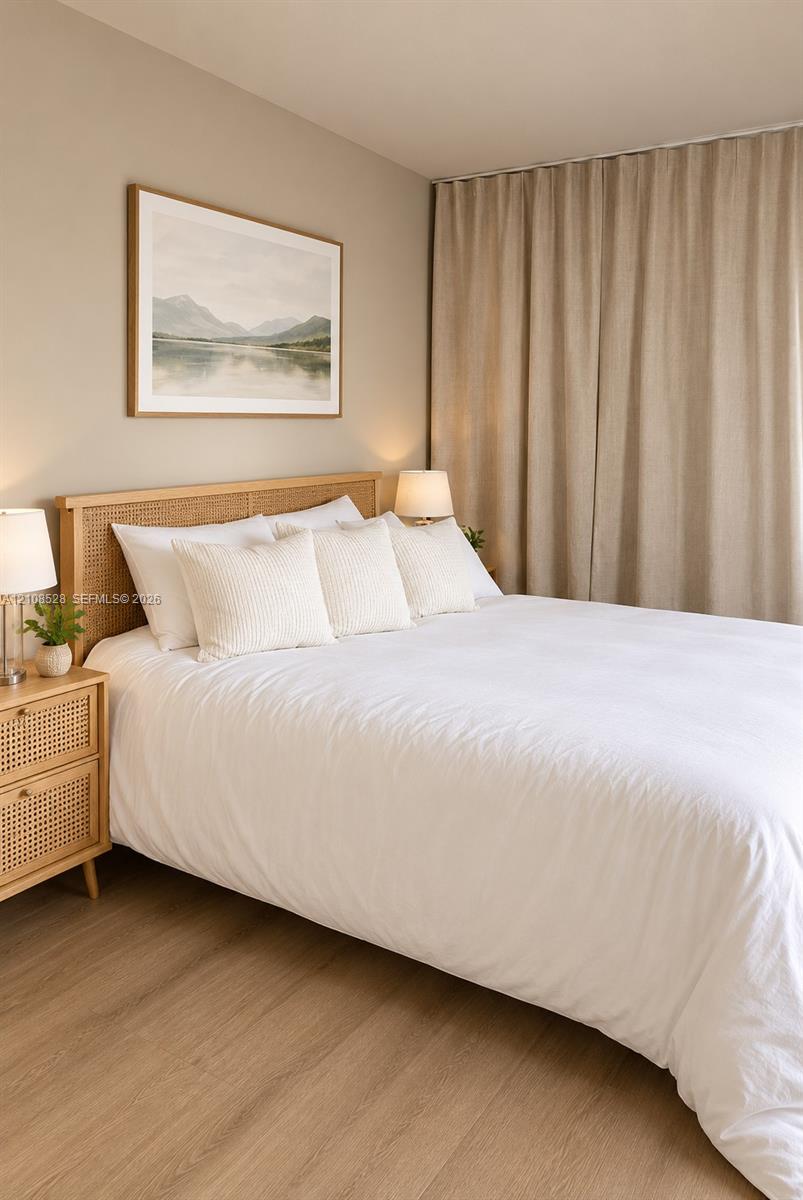 Neutral-toned interior space featuring wood-finish flooring and floor-to-ceiling drapery