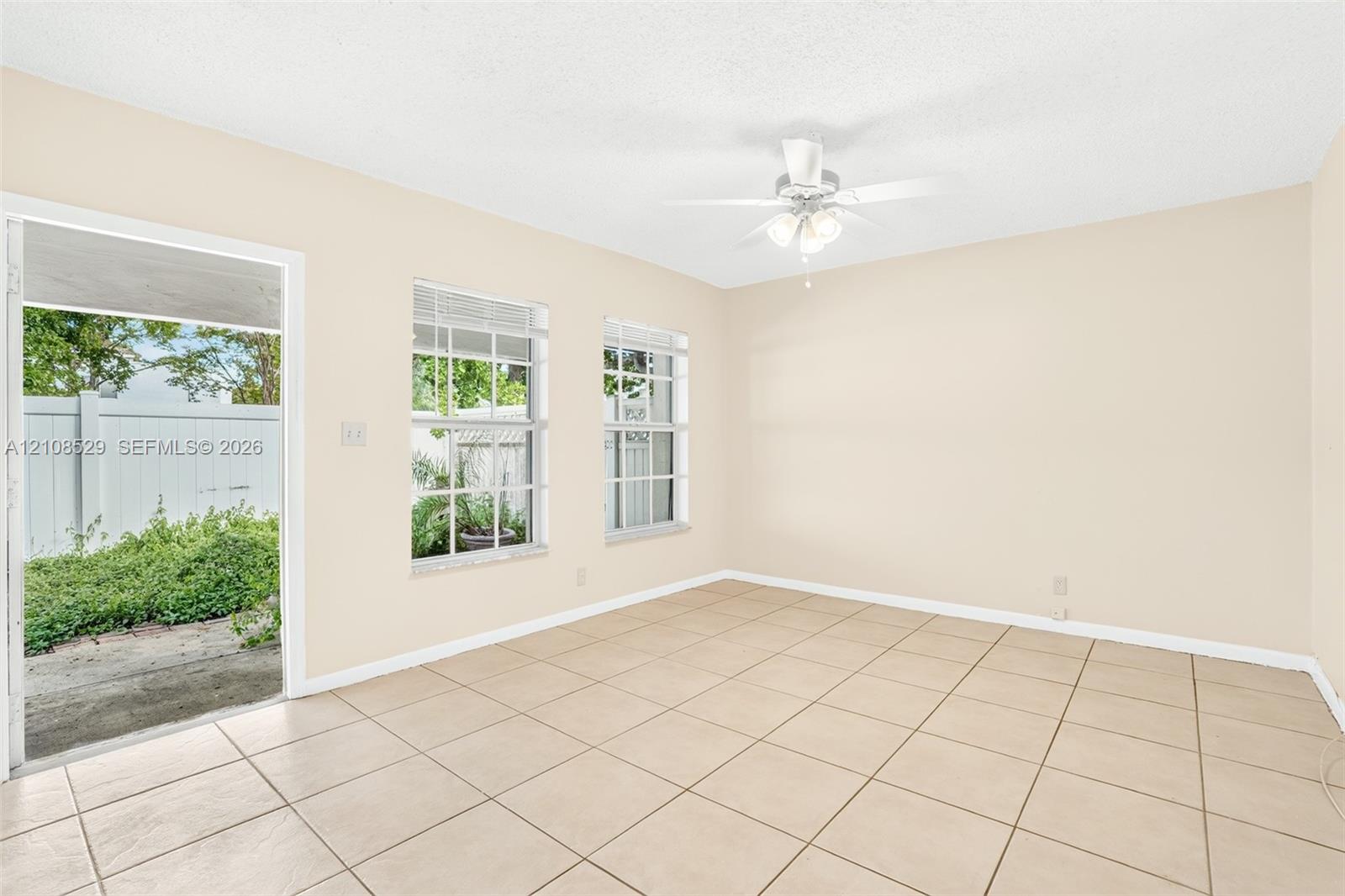 Interior space featuring neutral wall paint, ceramic tile flooring, two multi-pane windows, and a ceiling-mounted light fixture with fan