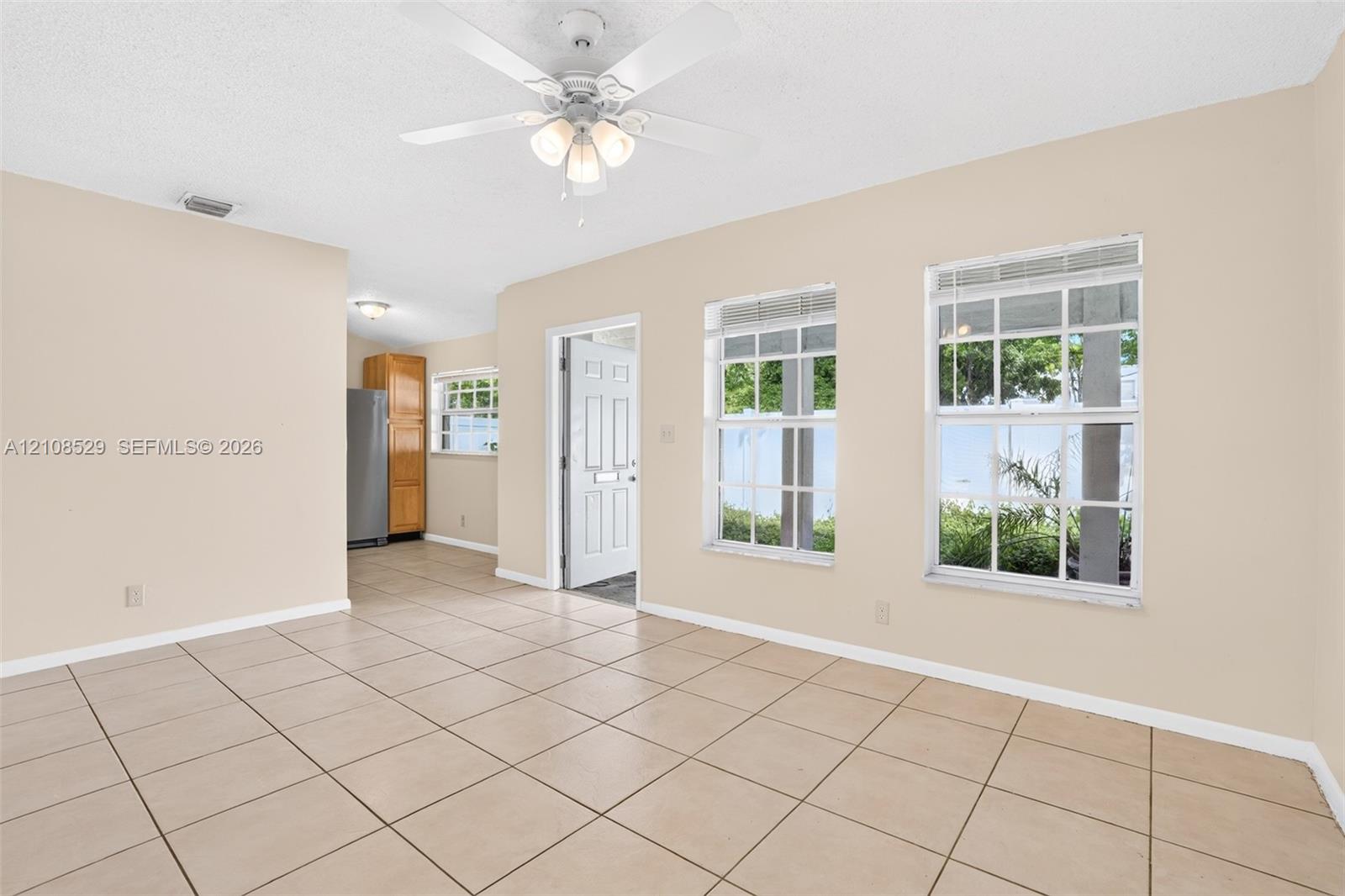 Interior featuring large-format tile flooring, a multi-blade ceiling fan with integrated lighting, and multiple windows with white muntin grids