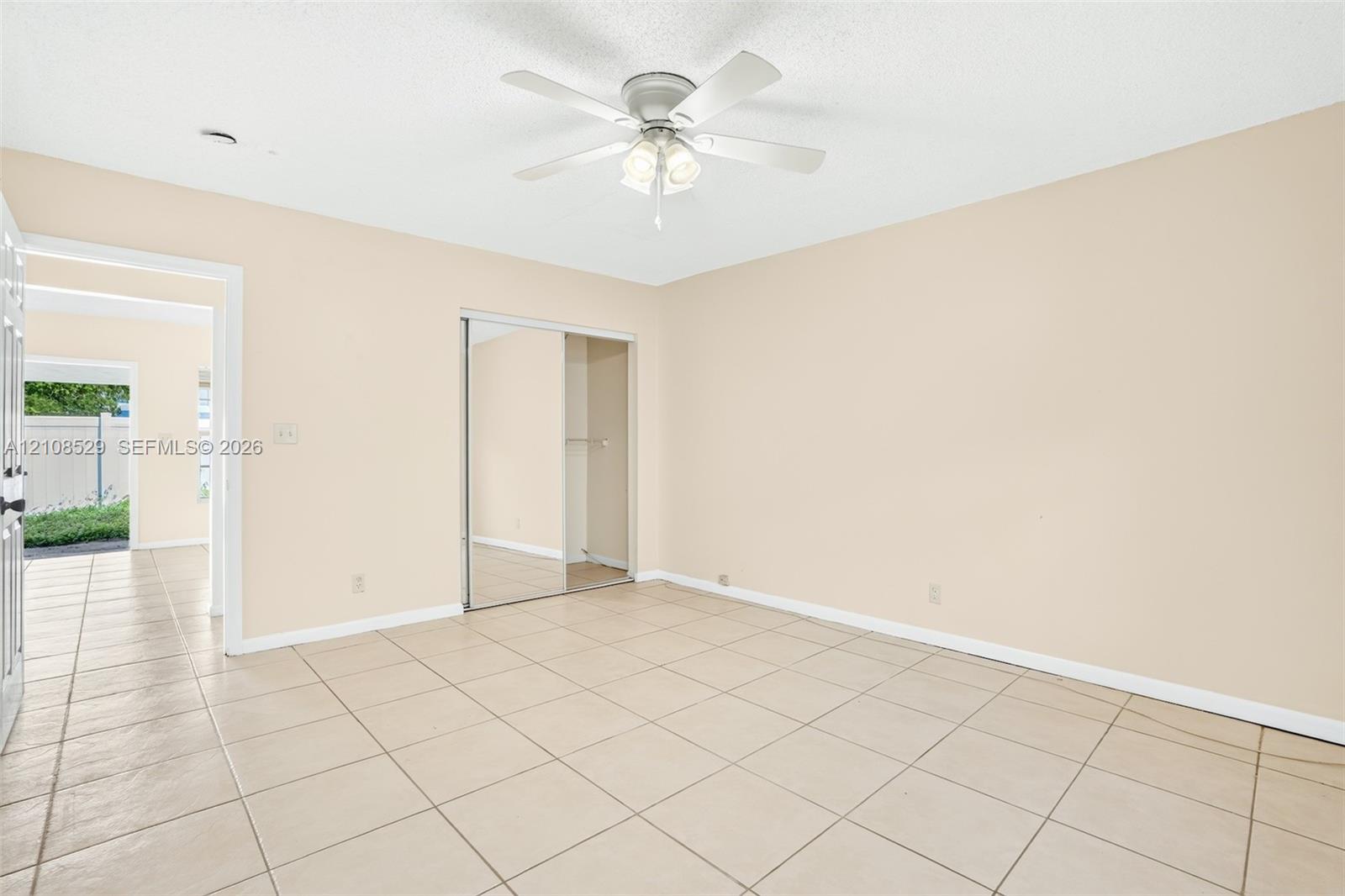 Neutral interior space featuring tile flooring, a ceiling fan with integrated lighting, and a closet with mirrored sliding doors