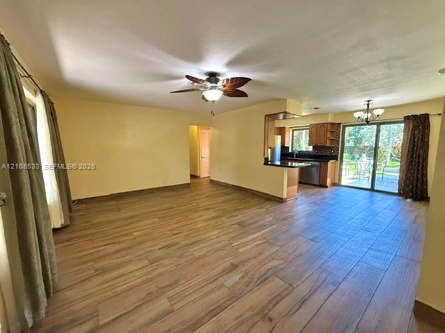 Open-concept interior featuring wood-finish tile flooring, a palm-leaf style ceiling fan, dark cabinetry, and sliding glass doors Open-concept interior featuring wood-finish tile flooring, a palm-leaf style ceiling fan, dark cabinetry, and sliding glass doors