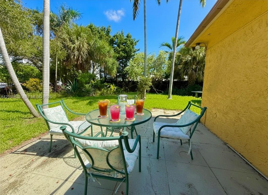 Rear patio featuring a concrete surface, texturized exterior wall, and established landscaping with palm trees Rear patio featuring a concrete surface, texturized exterior wall, and established landscaping with palm trees