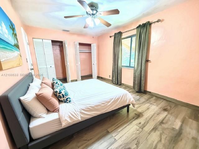 Wood-finish flooring, dual bi-fold door closets, and a ceiling fan with integrated lighting