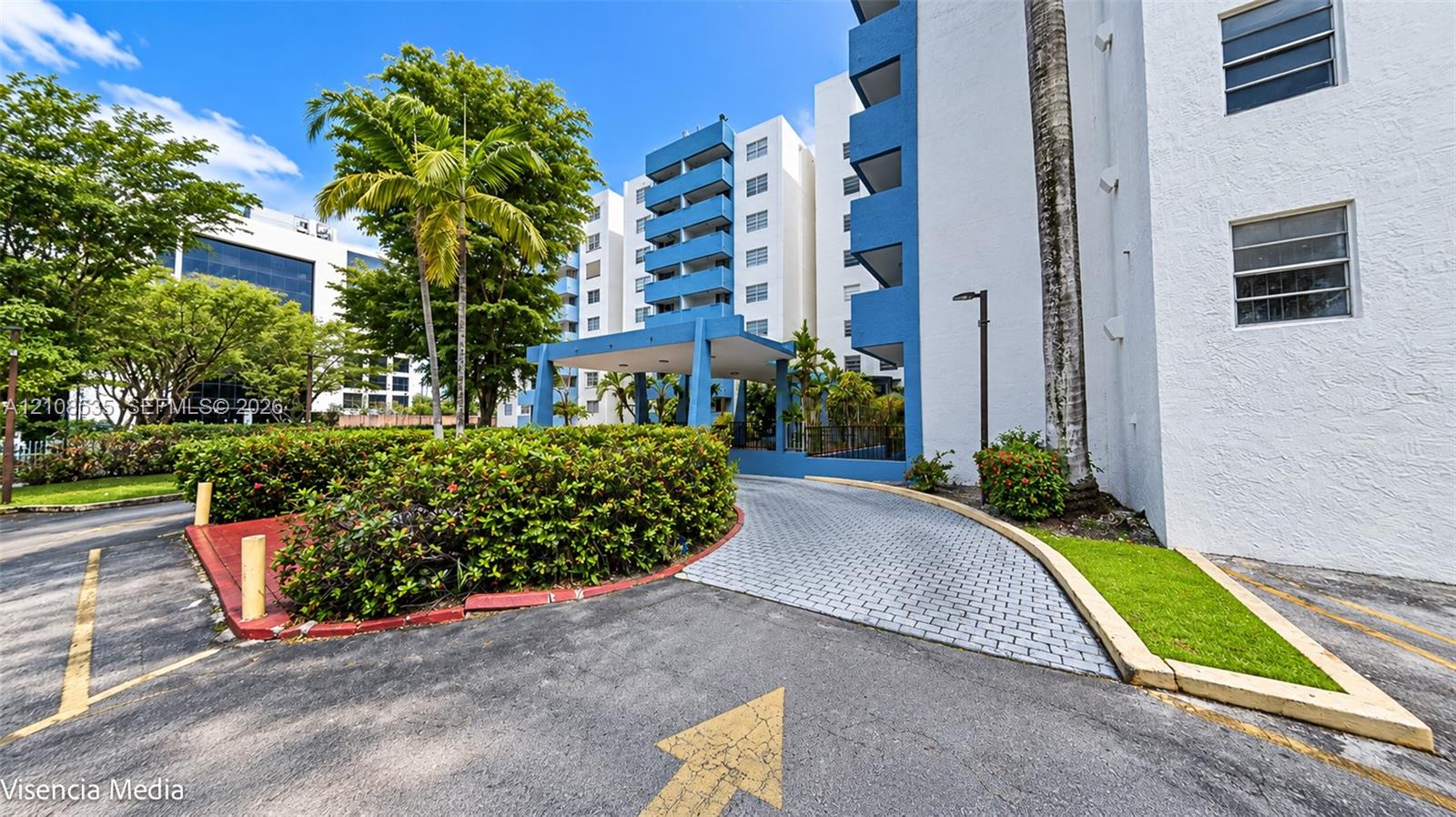 Multi-story exterior featuring a covered entryway, paved driveway, blue structural accents, and landscaped grounds Multi-story exterior featuring a covered entryway, paved driveway, blue structural accents, and landscaped grounds