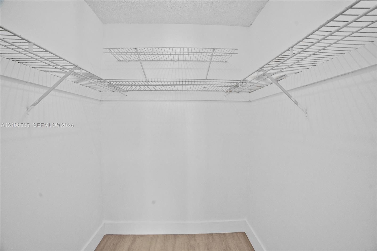 Storage space featuring dual-tier white wire shelving and light-toned wood-finish flooring