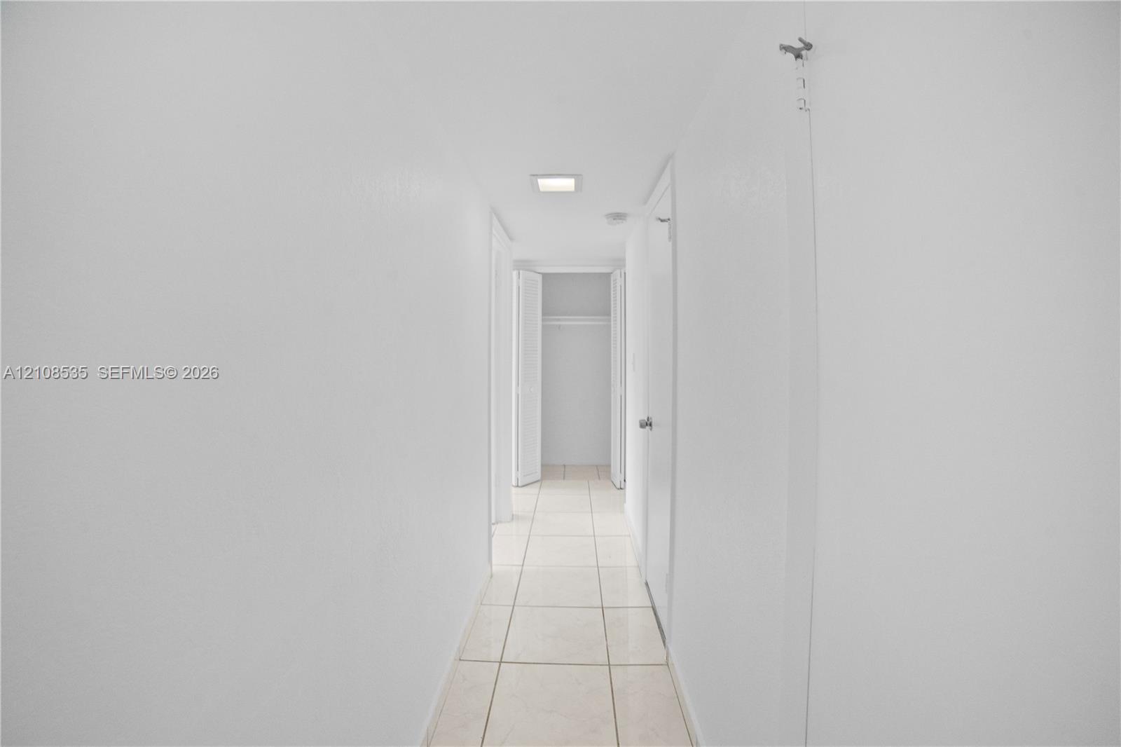 Hallway featuring neutral-toned tile flooring, recessed lighting, and built-in closet storage