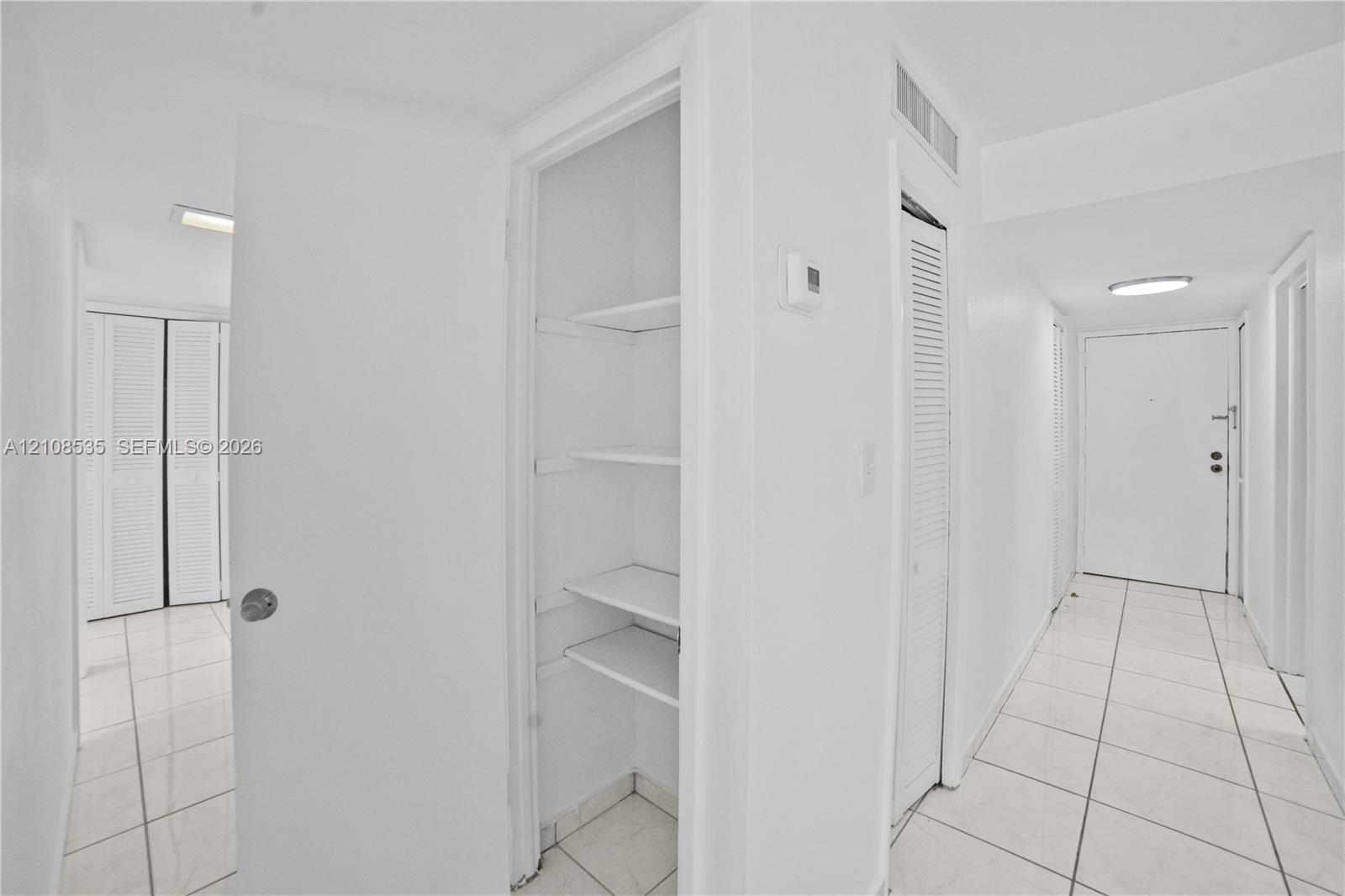 Ceramic tile flooring, louvered closet doors, and open-shelf built-in storage