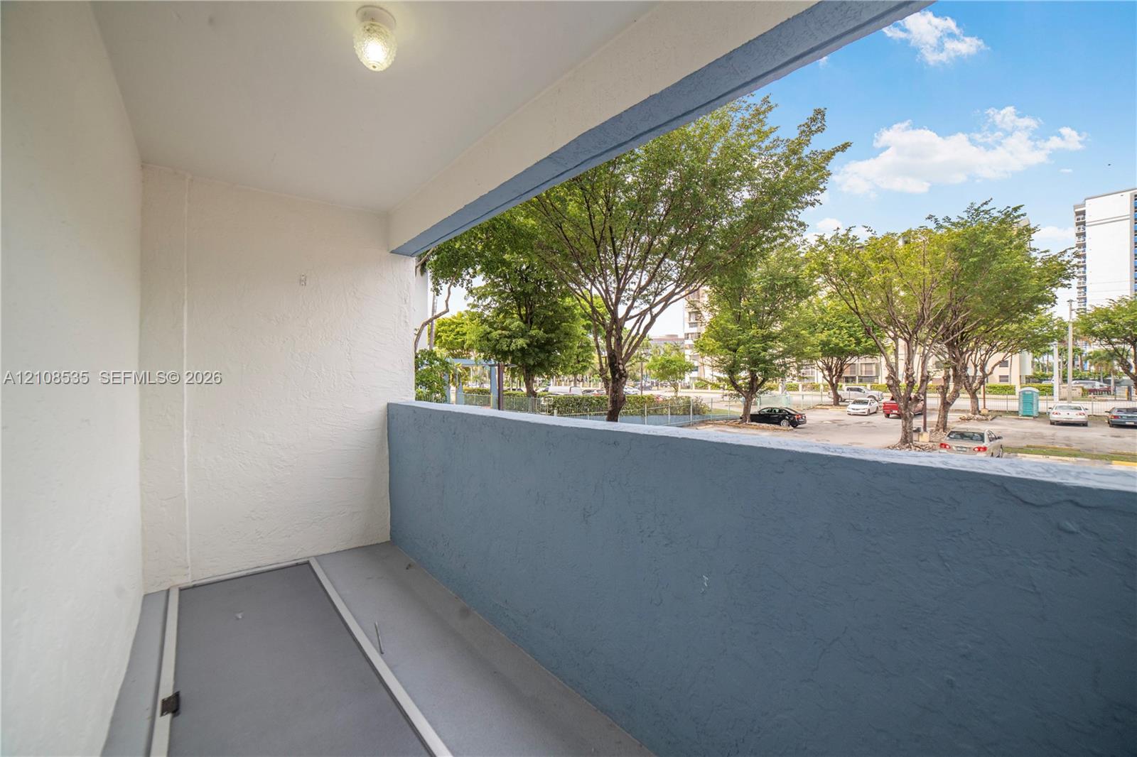 Covered balcony featuring textured walls, solid painted railings, and a surface-mounted ceiling light