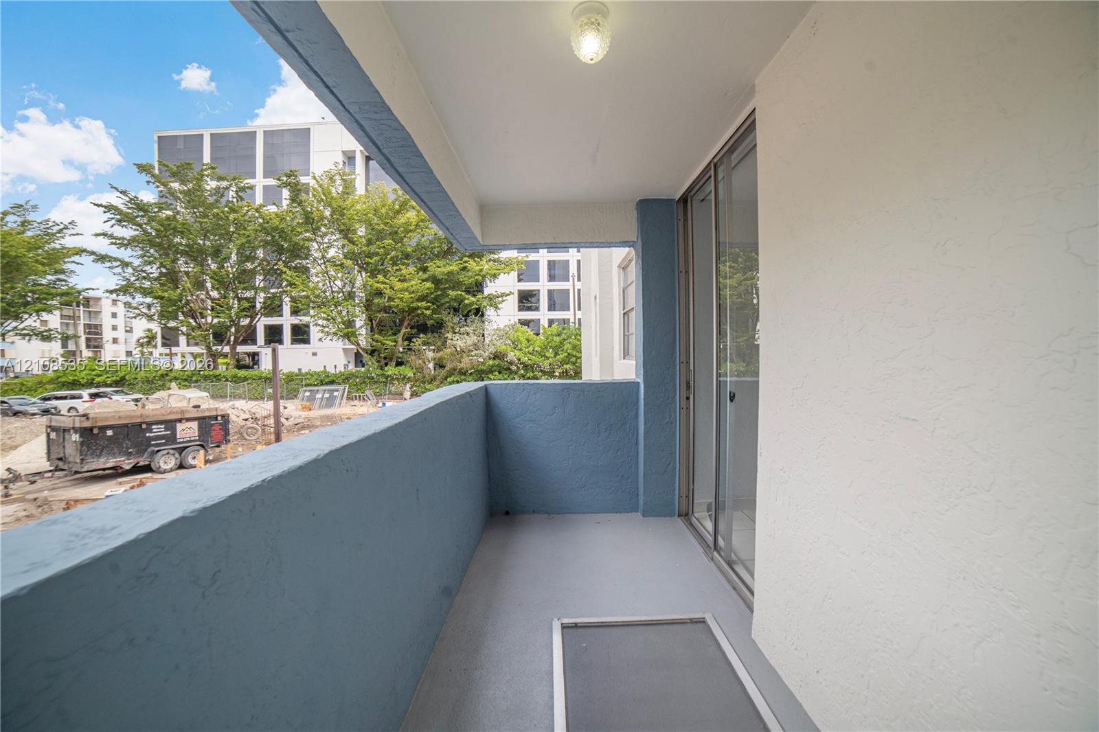 Private covered balcony featuring painted masonry walls, durable floor surfacing, flush-mount lighting, and sliding glass door entry