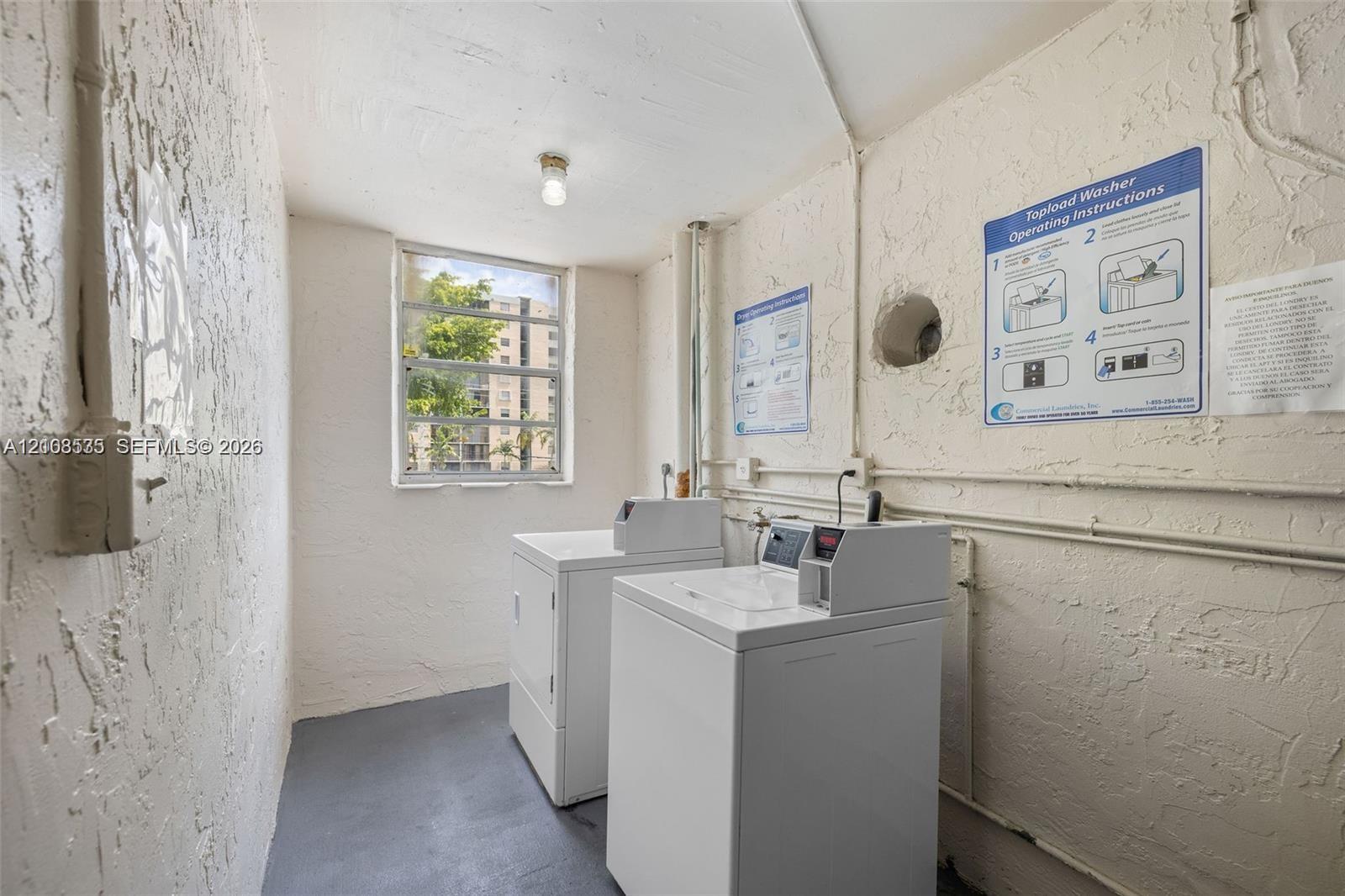 Laundry space featuring a multi-pane window, concrete flooring, and textured wall finish