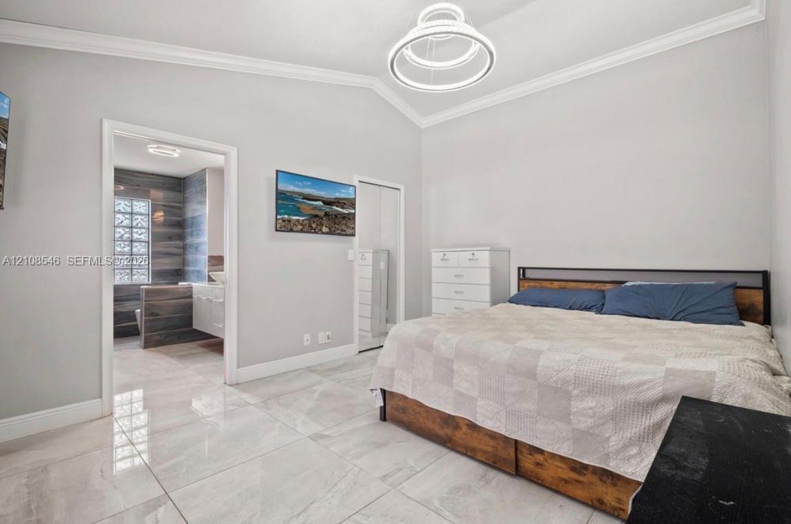 Vaulted ceilings with crown molding, polished stone-finish floor tile, and a contemporary multi-ring pendant light fixture