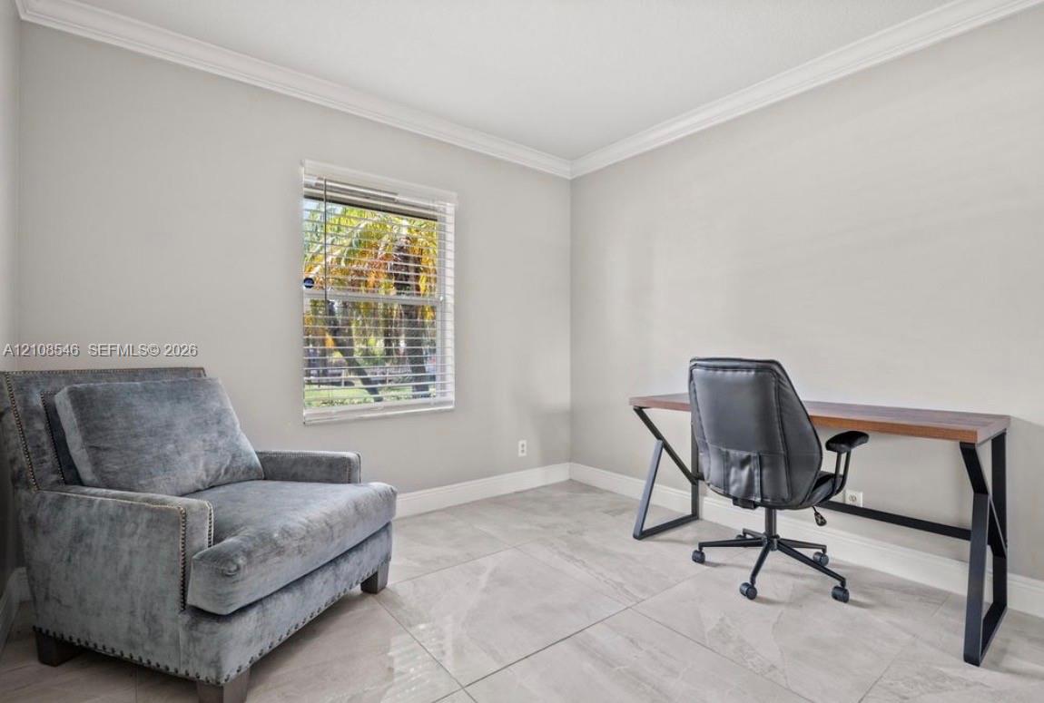 Neutral-toned walls with crown molding, large-format tile flooring, and window featuring horizontal blinds