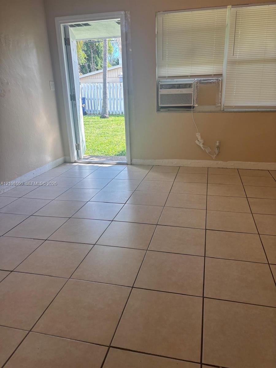 Ceramic tile flooring, neutral wall tones, window blinds, built-in window air conditioning unit, and direct exterior access