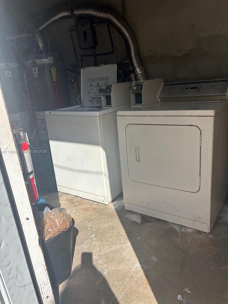 Dedicated laundry space featuring a top-load washer, a front-load dryer, and an integrated water heater unit with metal venting