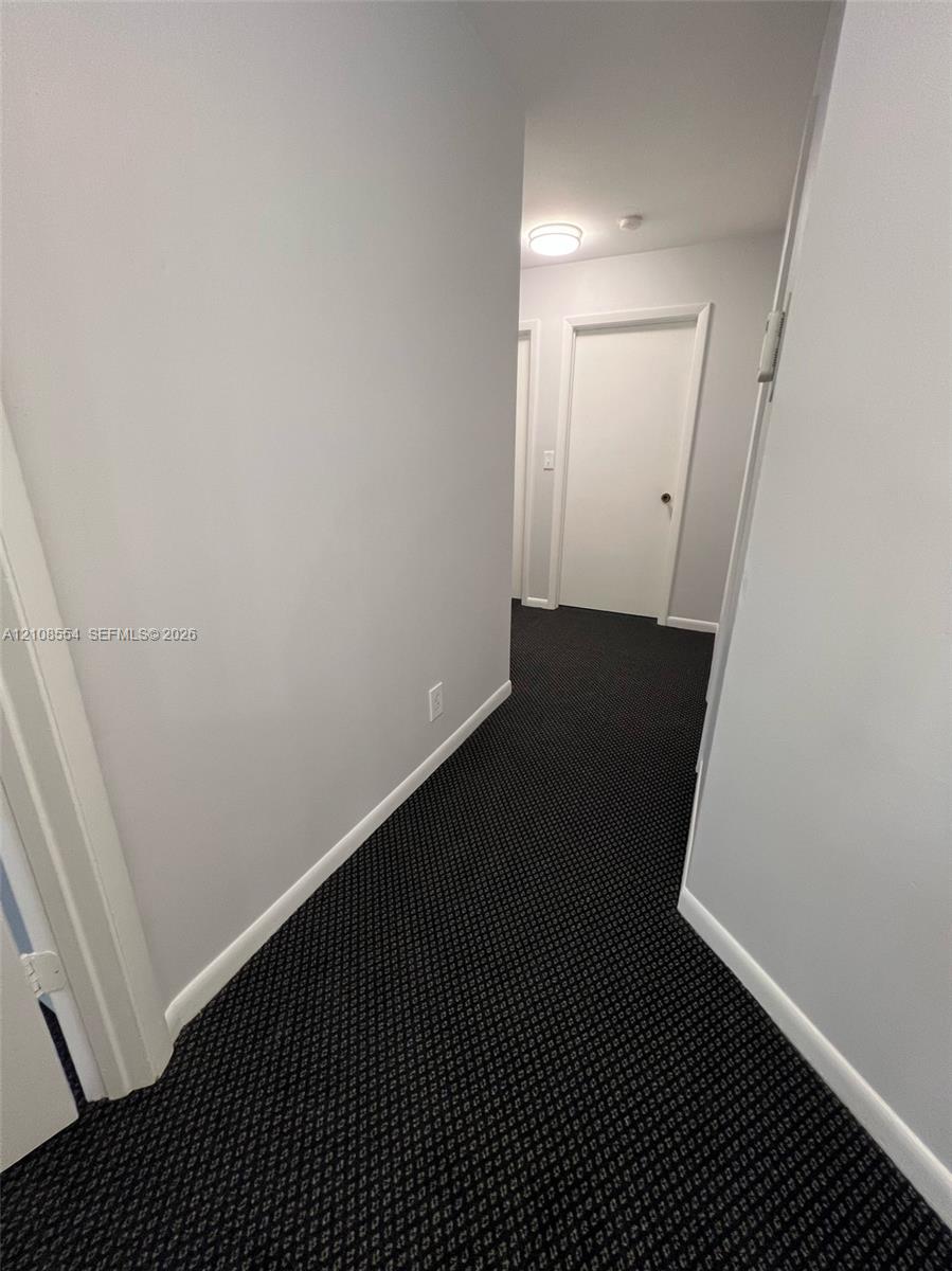 Hallway featuring patterned wall-to-wall carpeting, neutral-toned walls, and recessed ceiling lighting