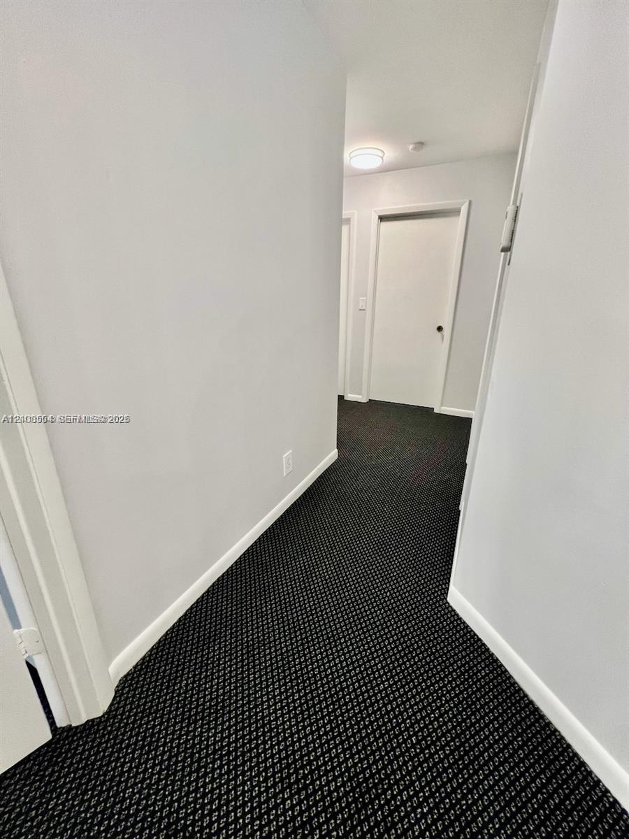 Hallway featuring patterned carpeting, neutral wall color, and flush-mount ceiling lighting