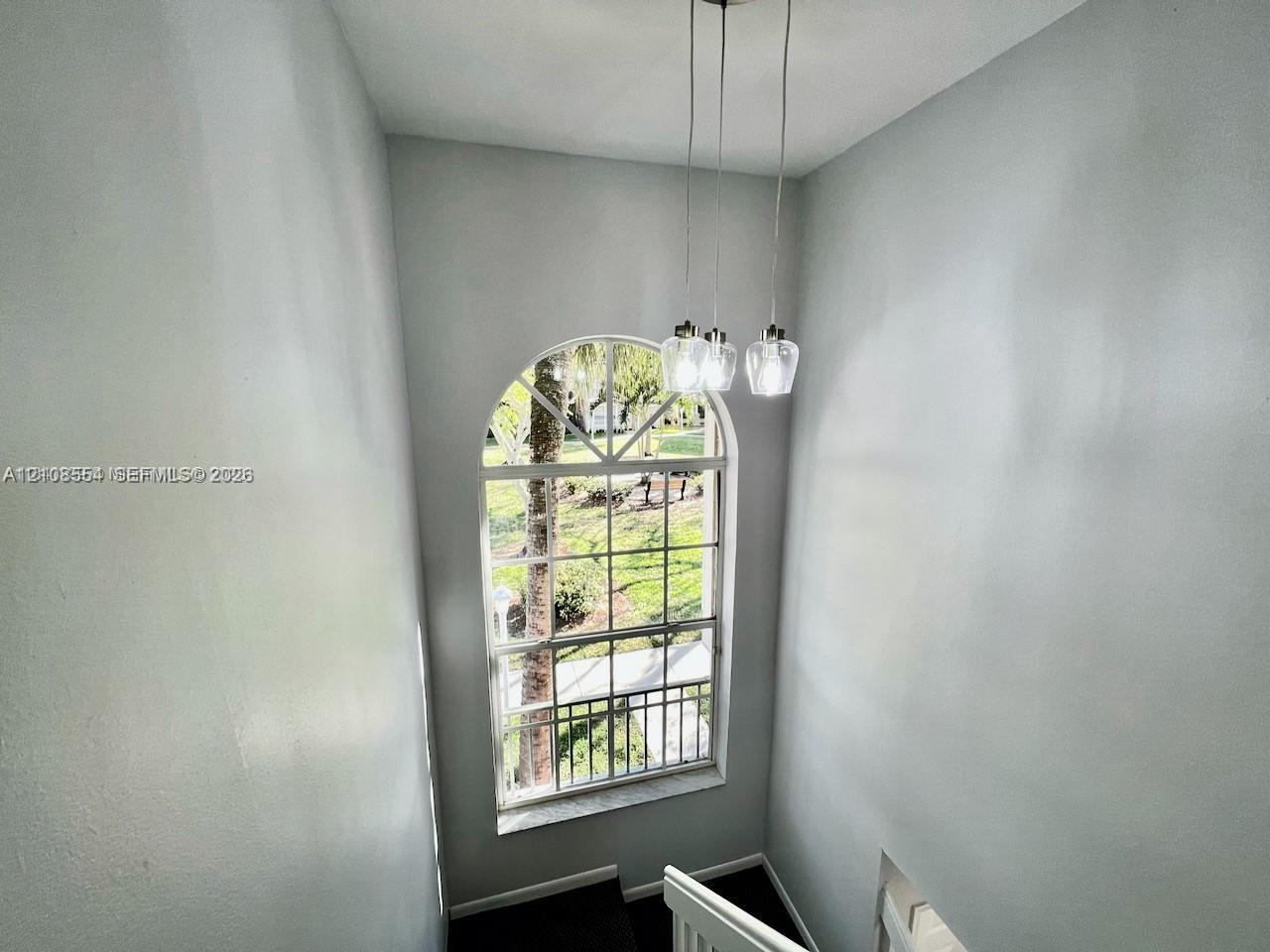 Multi-story space featuring an arched multi-pane window and a three-light pendant fixture