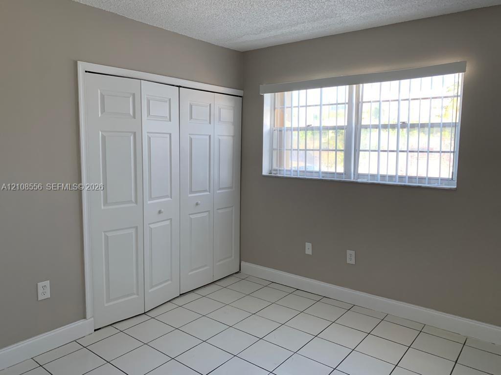 Room featuring white tile flooring, neutral wall paint, and a white paneled closet door