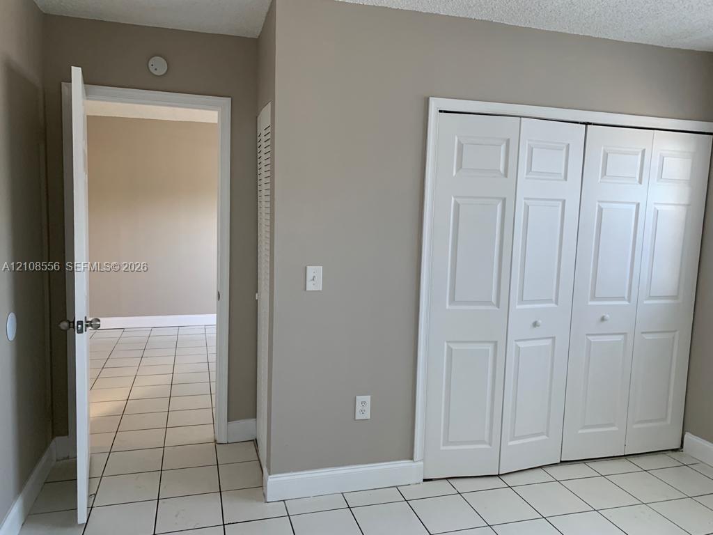 Neutral-tone walls, white ceramic tile flooring, and a multi-panel white closet door