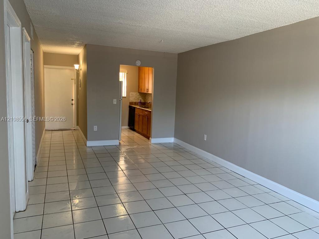 Interior space featuring light-colored tile flooring, neutral wall tones, and built-in cabinetry within the kitchen area Interior space featuring light-colored tile flooring, neutral wall tones, and built-in cabinetry within the kitchen area