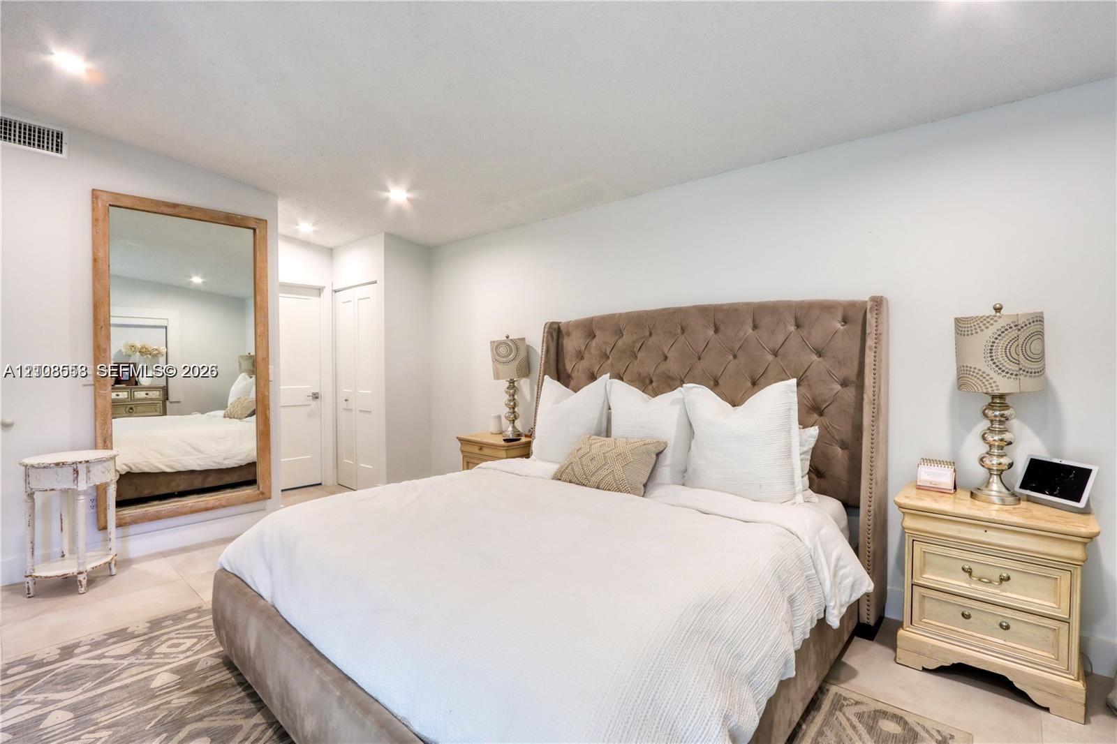Large wall-mounted mirror with a wood-finish frame and neutral flooring throughout