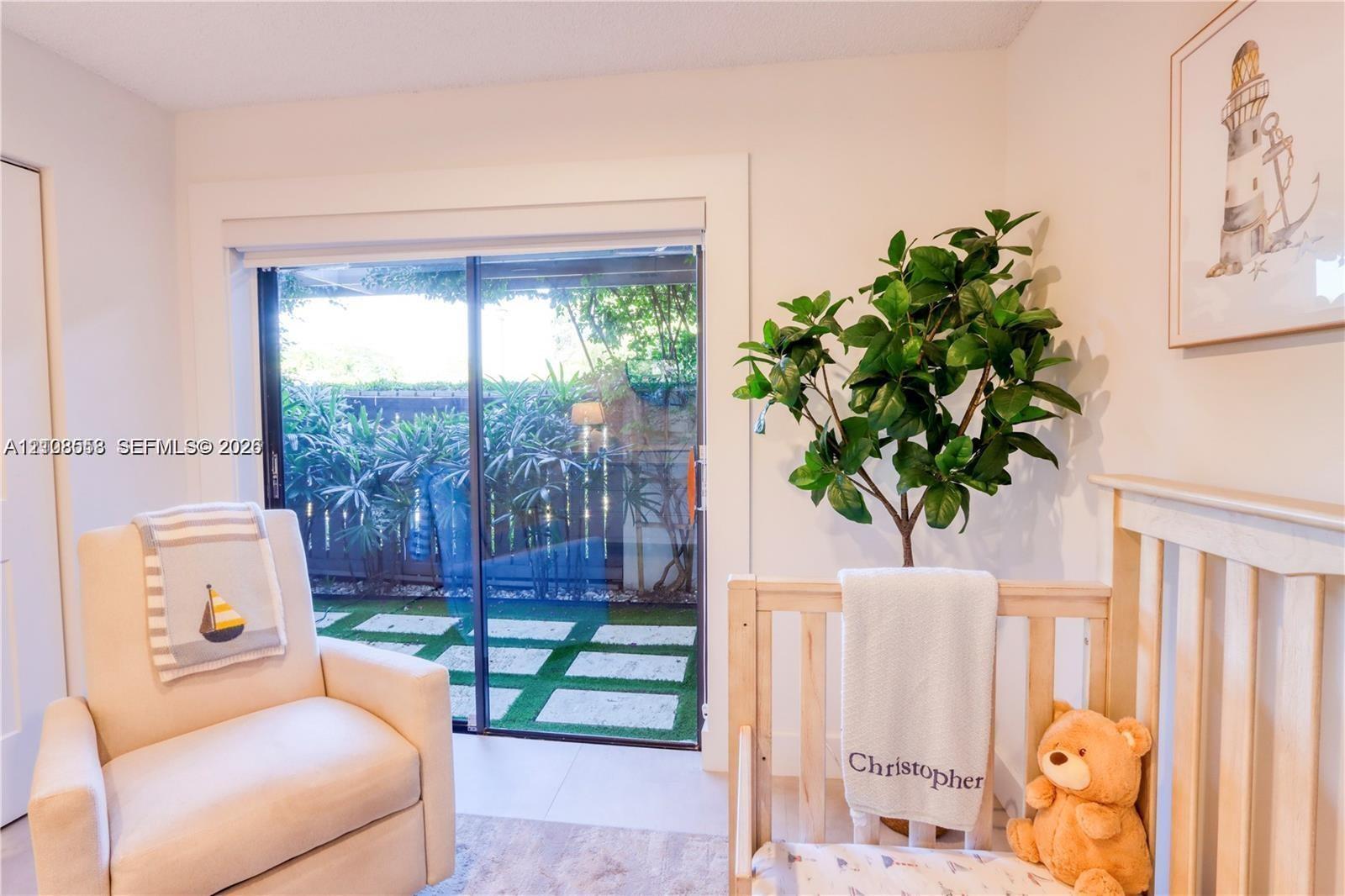 Sliding glass door with wide casing, stone-tile flooring, and access to a fenced patio area featuring stone pavers set in artificial turf