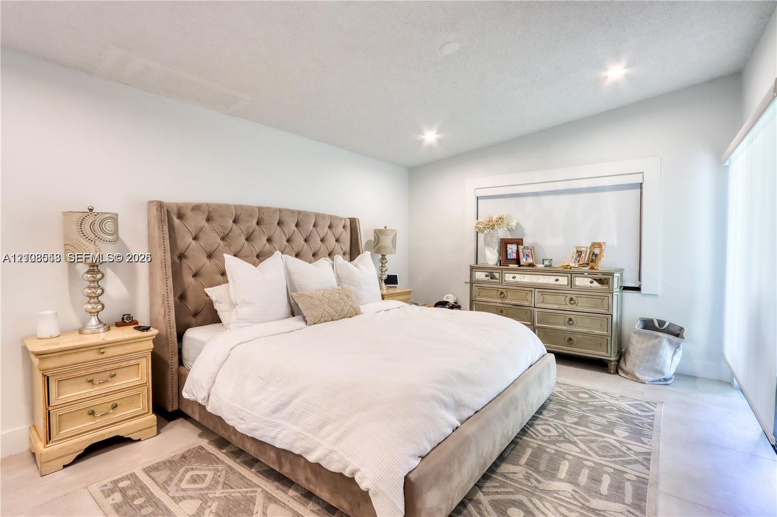 Spacious room featuring neutral tile flooring, recessed lighting, and large window with wide-slat blinds