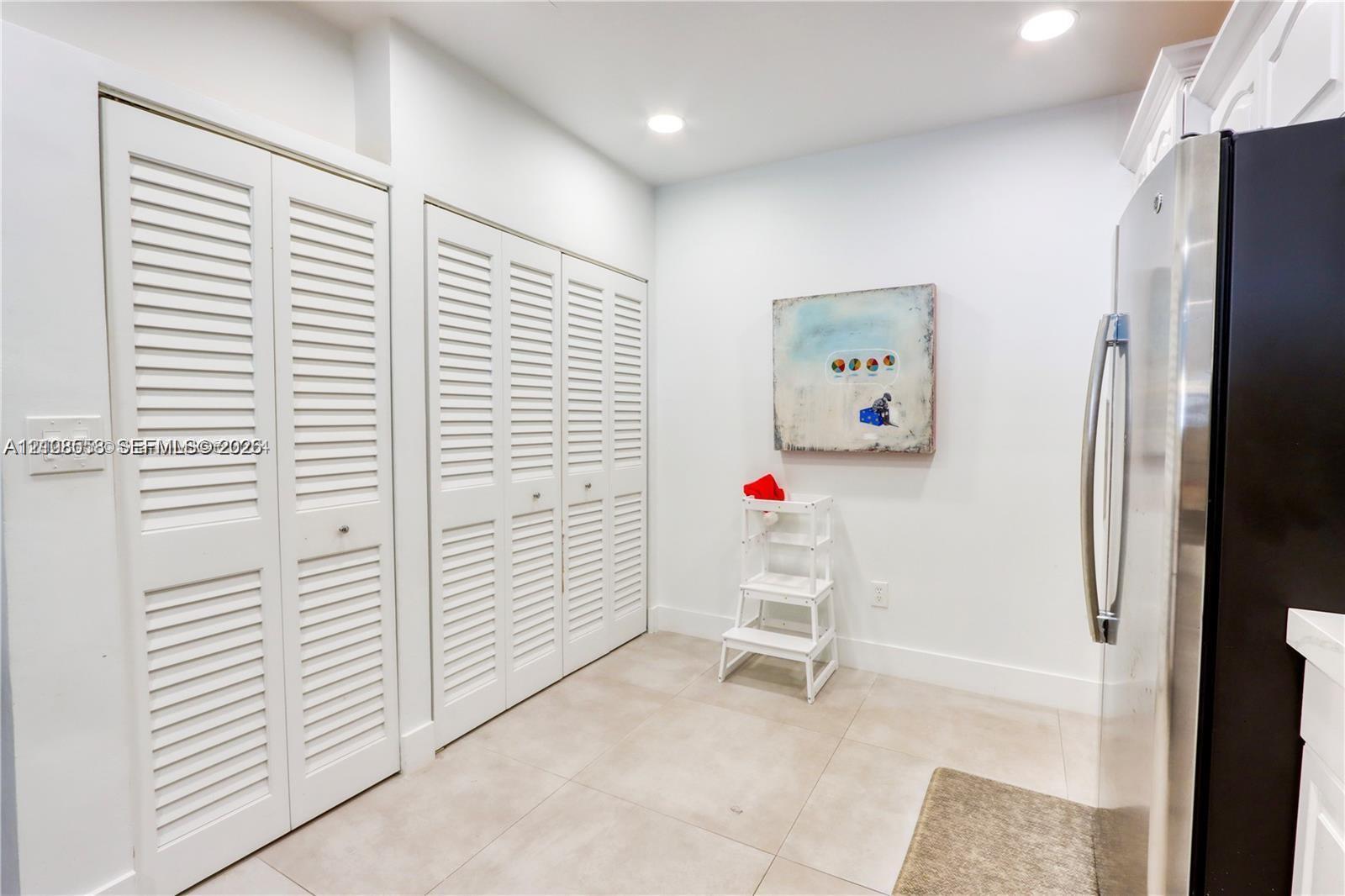 Large-format tile flooring paired with floor-to-ceiling white louvered closet doors and recessed lighting