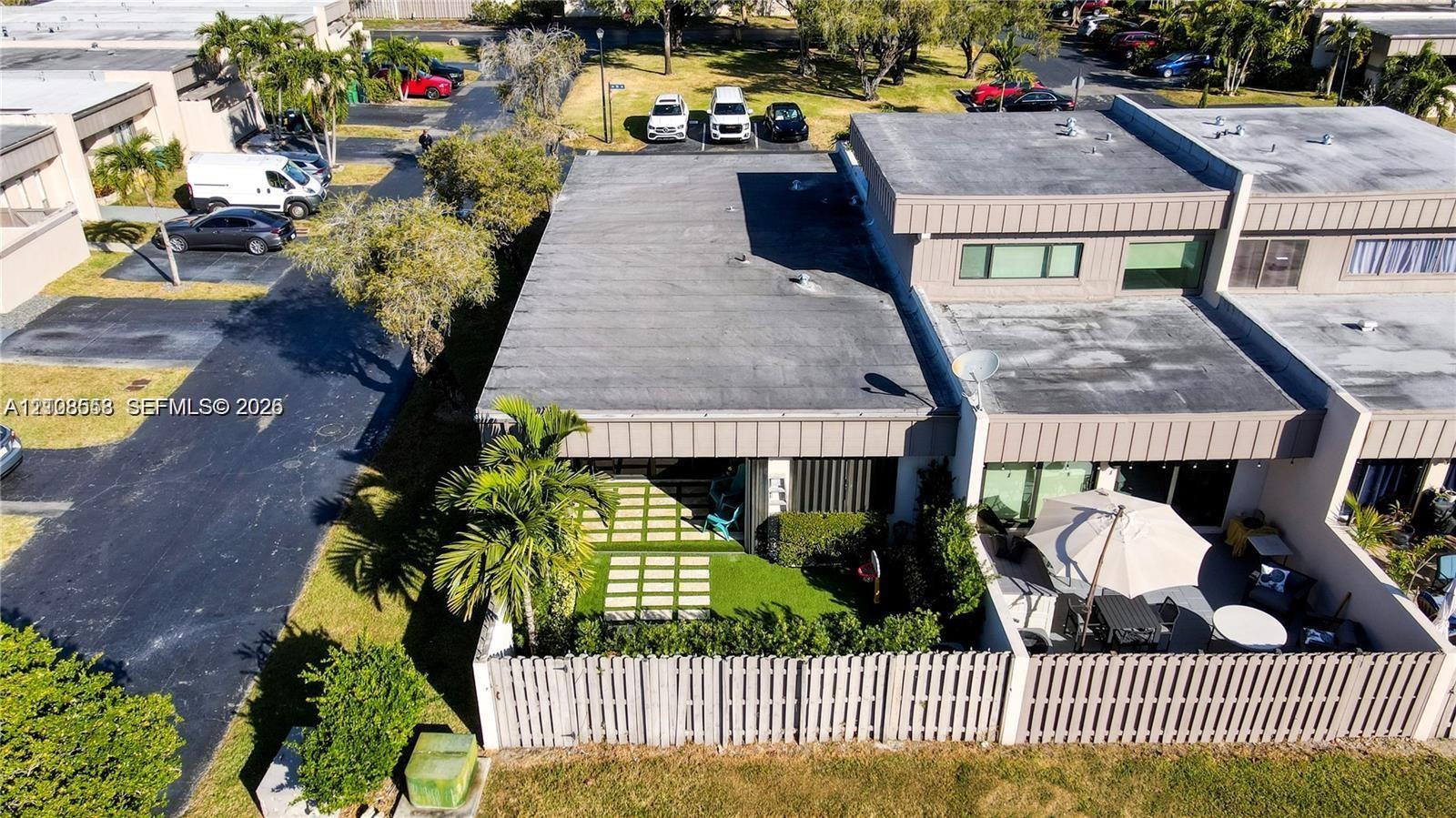 Multi-unit residential structure with flat roofing and a private, fenced-in patio area featuring paver-and-turf hardscaping