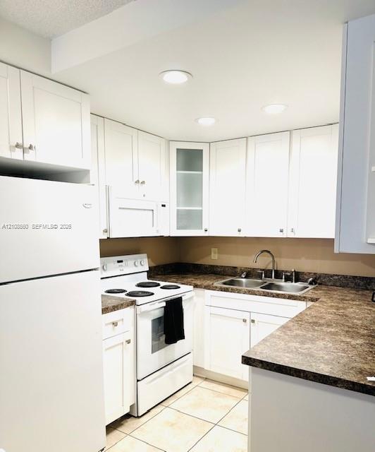 Kitchen featuring white cabinetry with glass-panel accents, stone-patterned laminate countertops, double-basin stainless steel sink, recessed lighting, and tile flooring