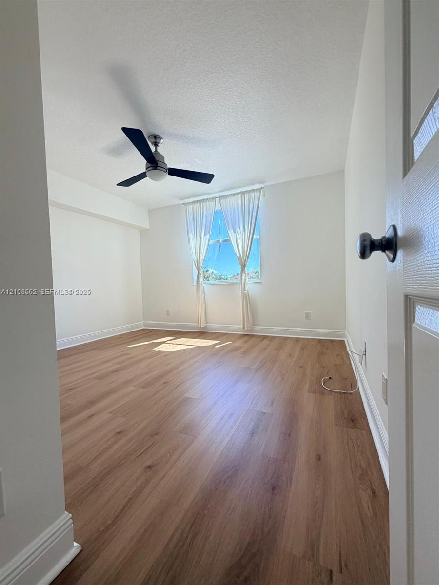 Interior space featuring wood-finish flooring, neutral wall paint, and a modern ceiling fan