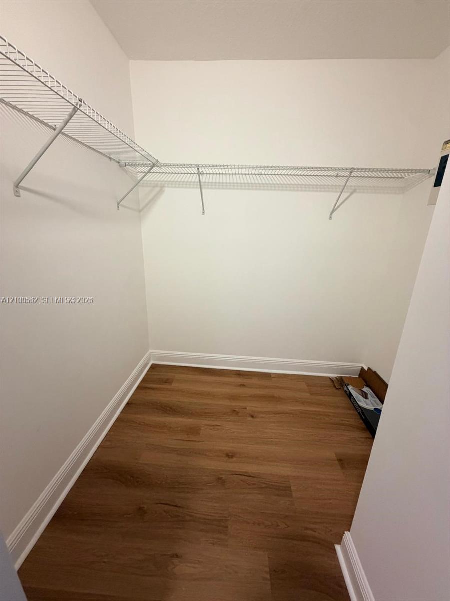 Walk-in storage space featuring wood-finish flooring and white wire shelving