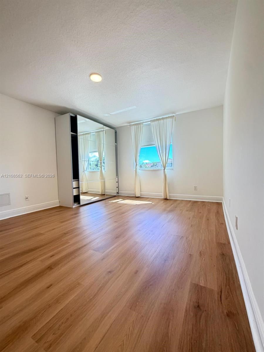 Room featuring wood-finish flooring, recessed lighting, and a built-in mirrored wardrobe