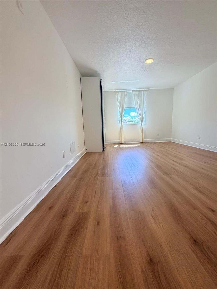 Interior space featuring wood-finish flooring, a built-in floor-to-ceiling storage cabinet, and recessed ceiling lighting