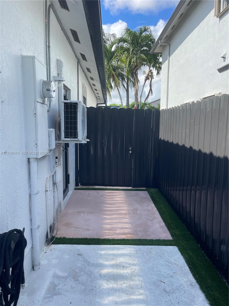 Side yard featuring a concrete patio, synthetic turf surfacing, and privacy fencing