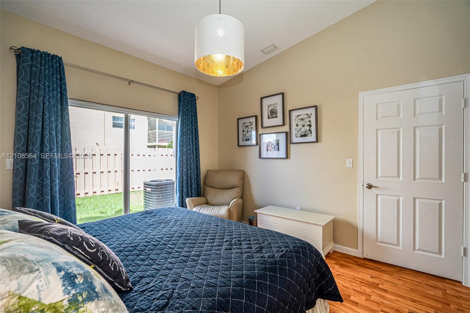 Vaulted ceilings with a drum-style pendant light, wood-finish flooring, and sliding glass doors with exterior access