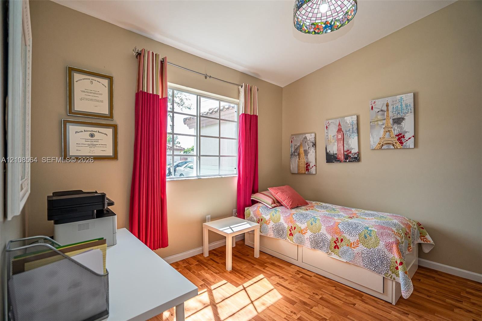 Room featuring wood-finish flooring, a multi-pane window, and a stained-glass style pendant light fixture