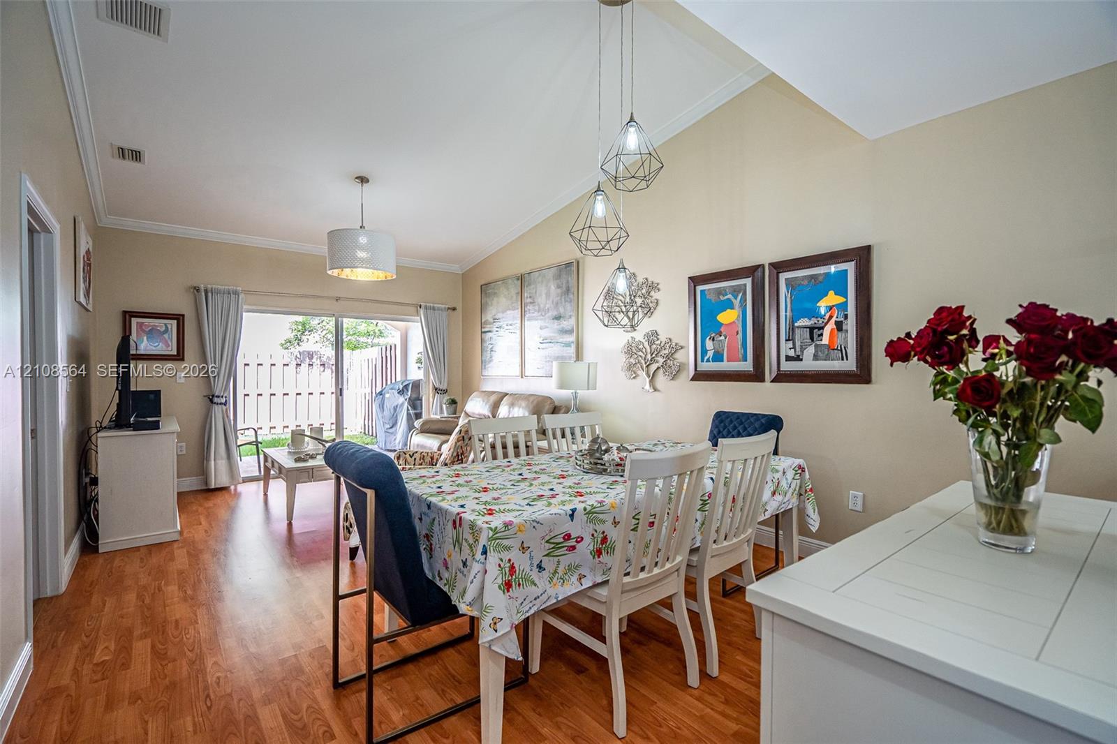 Vaulted ceilings, wood-finish flooring, sliding glass patio doors, and geometric pendant lighting
