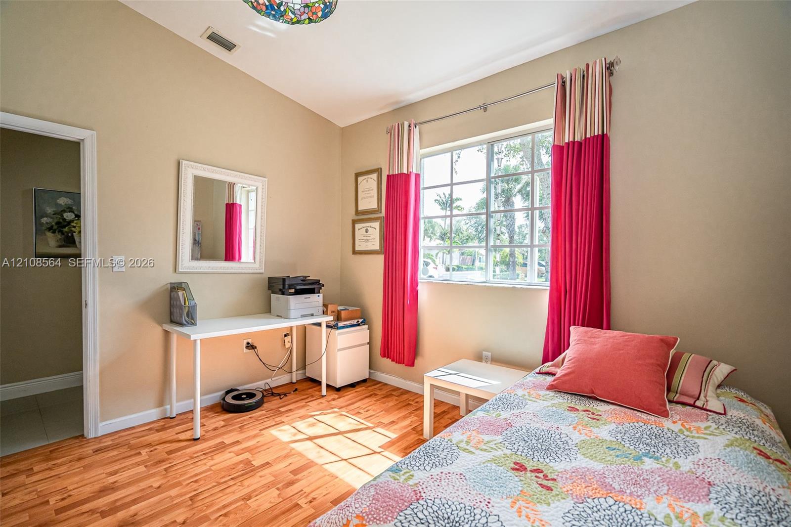 Room featuring vaulted ceilings, wood-finish flooring, and a large grid-pattern window