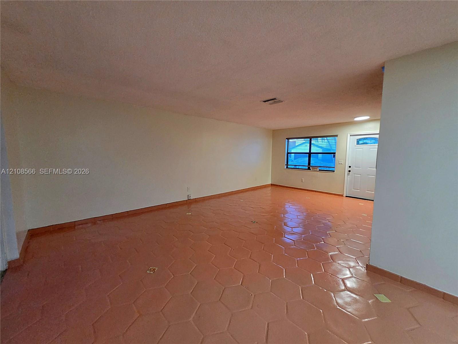 Open-concept interior featuring hexagonal tile flooring, neutral wall finishes, and a single-entry door with glass detail