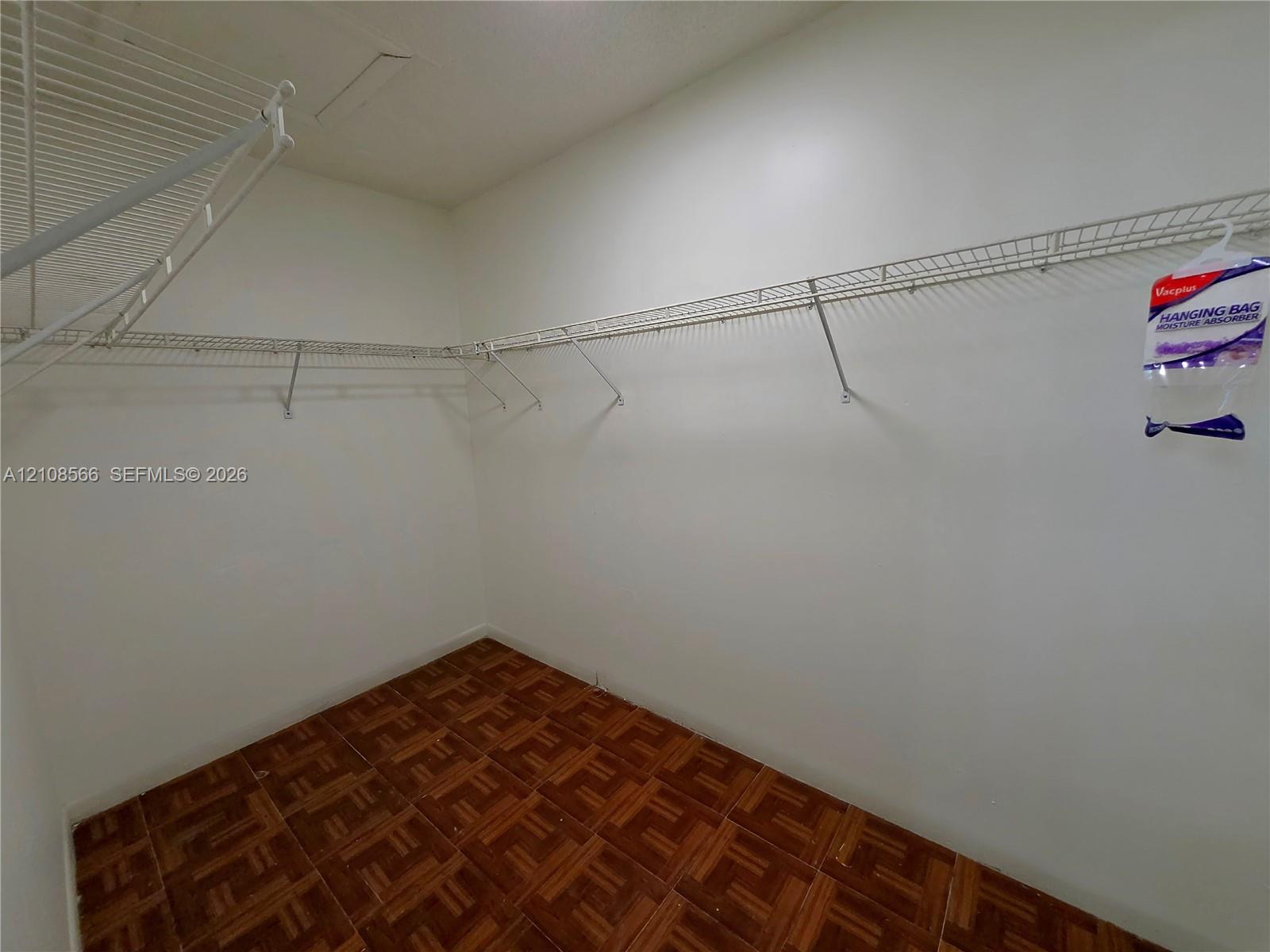 Storage space featuring white walls and wire shelving systems installed with wood-finish flooring
