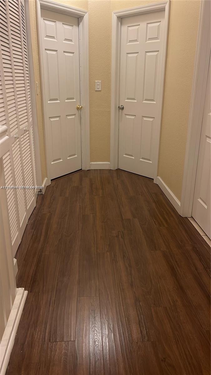Wood-finish flooring, two six-panel interior doors, and white louvered closet doors